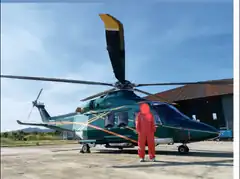 person in red jumpsuit standing in front of green helicopter