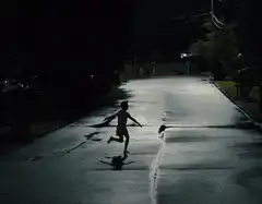 Silhouette of a child running down a dark street