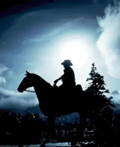 Silhouette of cowboy riding horse at night