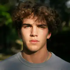 Young man with curly hair looking at camera
