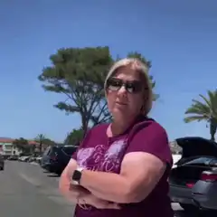 Woman in parking lot crosses arms and gestures