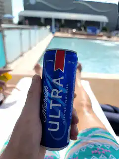 Person holding Michelob Ultra by pool