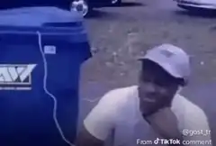 Man laughing next to blue dumpster