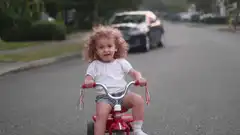 Toddler riding tricycle down street