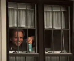 Man holding beer behind window bars