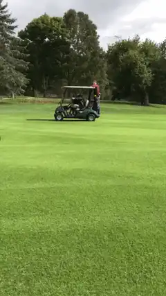 Man pulled by golf cart on green