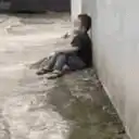 Sad child sitting against a wall