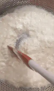 Stirring cottage cheese in a colander