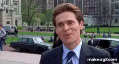 Willem Dafoe smirking in a suit