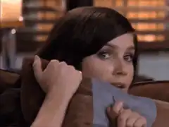 Girl hiding behind pillow peeking