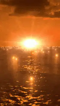 Sunset over ocean with city lights
