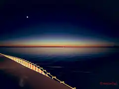 sunset over calm sea with pier railing
