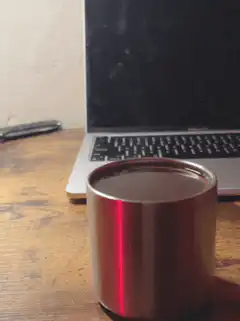 Red light reflection on metal cup near laptop