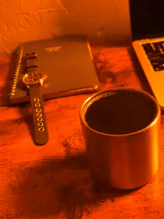 watch on notebook next to coffee mug
