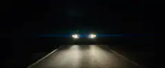 car headlights on dark road at night