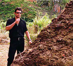 Man smoking next to a large rock