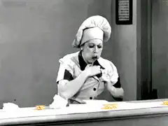 Woman in chef hat eating rapidly