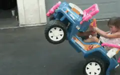 girl in toy jeep doing wheelie