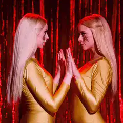 Two women in gold dresses touching hands