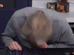 man facepalms and puts head on desk