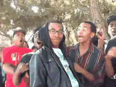 Guy in hoodie smiles while friends react