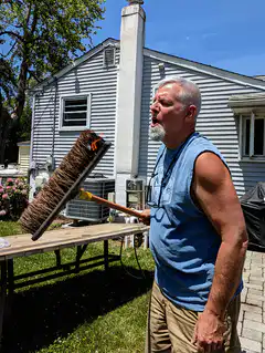 man blows dust off chimney brush