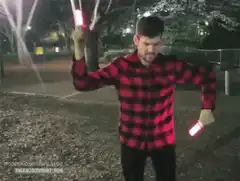 Man dancing with glow sticks in park