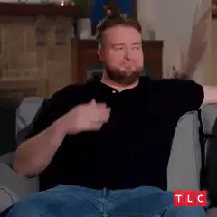Man shrugs and smiles on couch