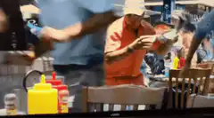 Man in orange shirt eating at a table