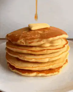 Syrup poured on pancakes with butter