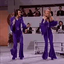 Elton John and Cher singing in purple