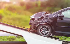 crashed black car on tow truck