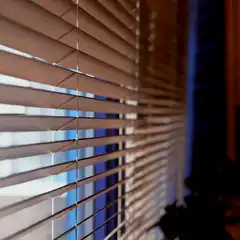 Woman peeks through blinds shocked