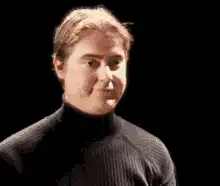 Man in turtleneck nodding and smiling