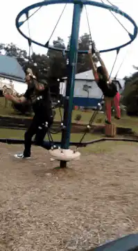 Man and woman spinning on playground merry-go-round