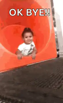 Baby slides down orange tube saying OK BYE
