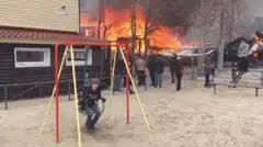 Kids swing in playground while house burns