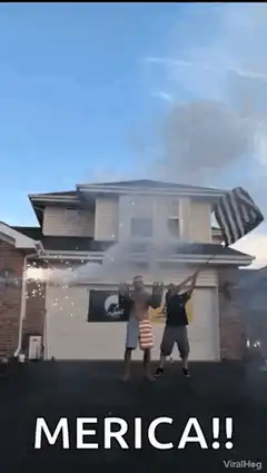 Two men celebrate with fireworks and an American flag
