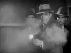 Man in fedora shoots gun in black and white