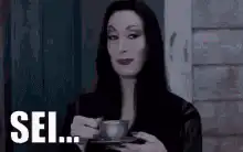 Morticia Addams sipping tea