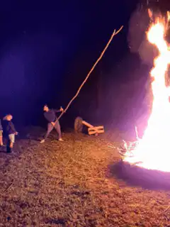 Man poking giant bonfire with long stick