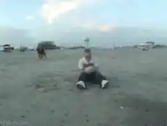 man sitting on beach gets hit by water balloon
