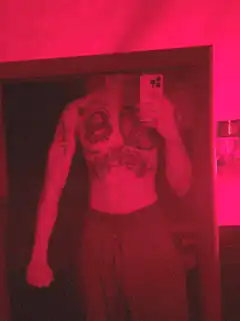 man with chest tattoos in red light