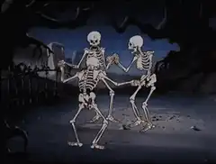 Three skeletons dancing in a graveyard