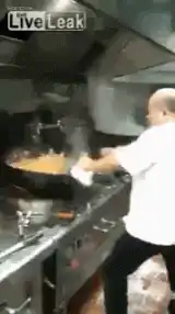 Chef flambéing food in a wok