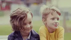 Two young boys sitting together outdoors
