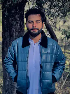 Man in blue puffer jacket by tree