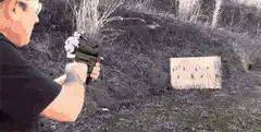 Man shooting paintball gun at wooden target