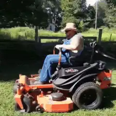 Man on riding mower waves hat