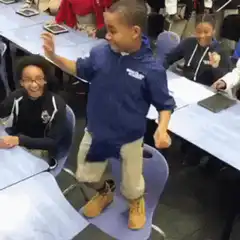Boy dancing on chair in classroom